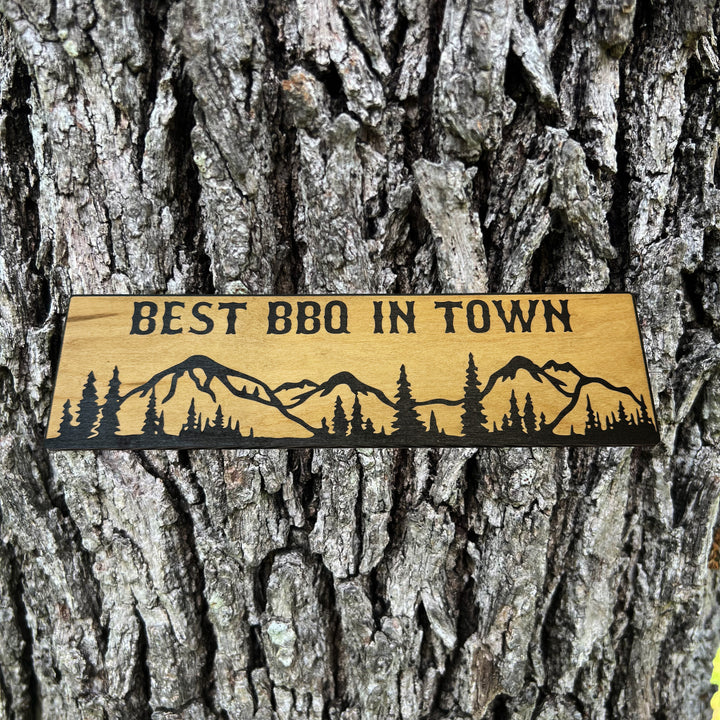 HipFlaskPlus Best BBQ in Town mountain scene black and natural wood sign on a tree trunk
