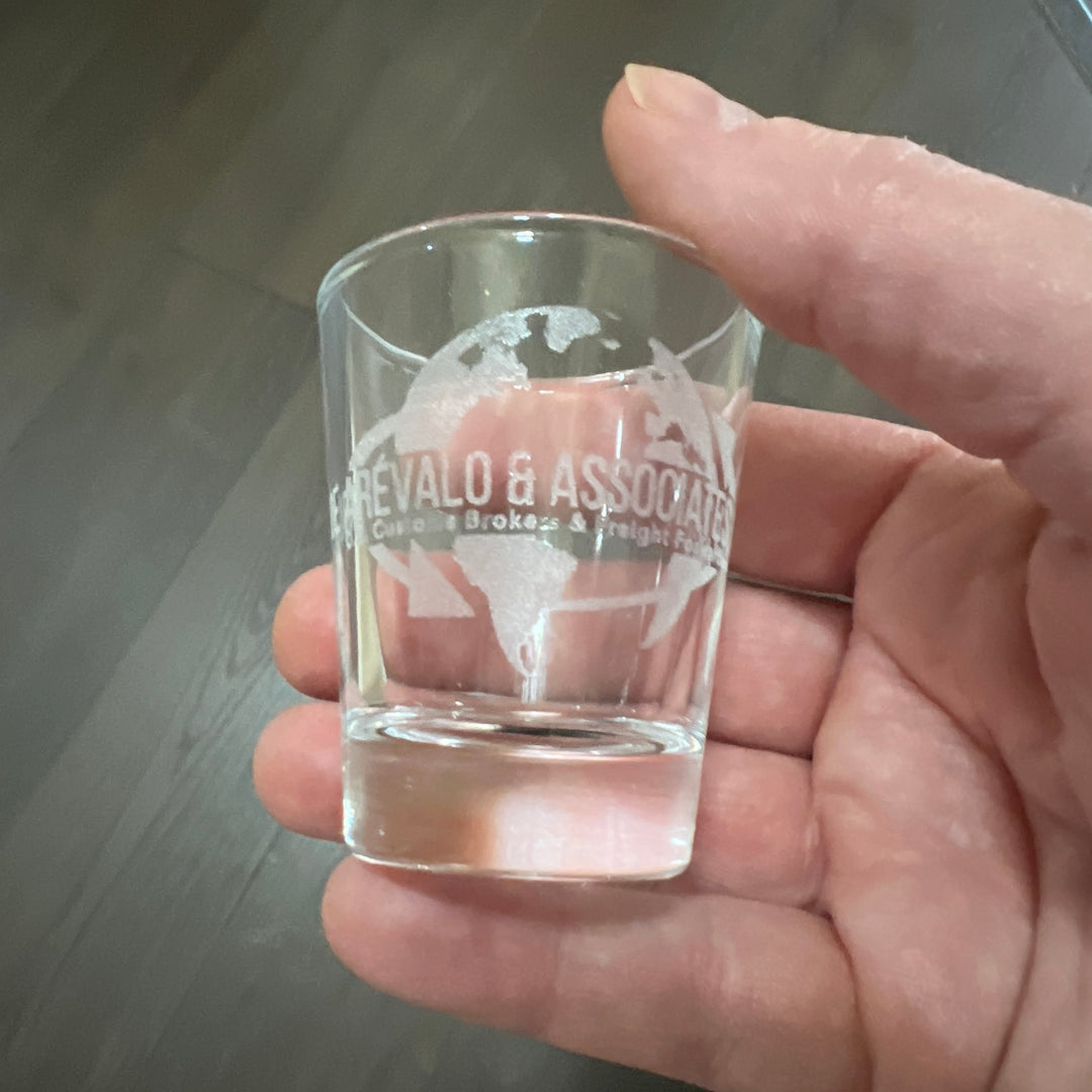Hand holding a HipFlaskPlus shot glass engraved with a custom logo