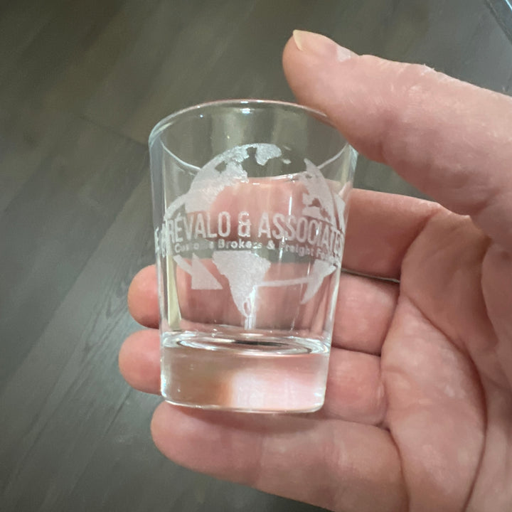 Hand holding a HipFlaskPlus shot glass engraved with a custom logo