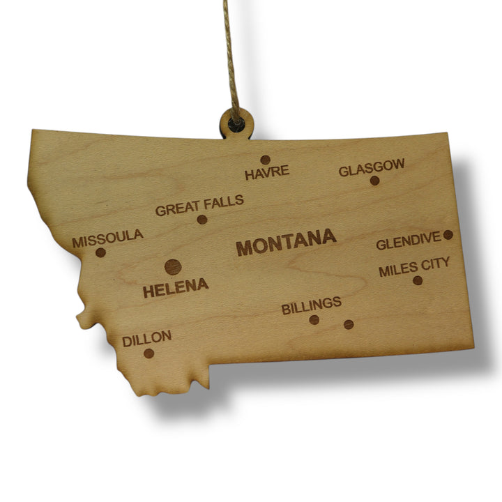Hand holding a HipFlaskPlus custom Montana state ornament with cities in a snowy landscape