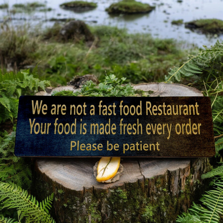 HipFlaskPlus custom We Are Not a Fast Food Restaurant Please Be Patient sign in black in a garden
