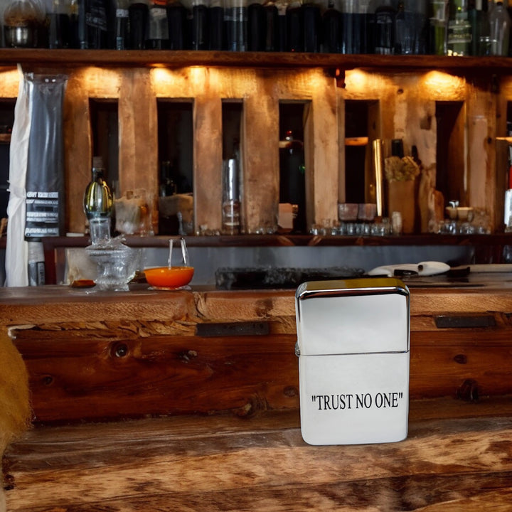 HipFlaskPlus Trust No One chrome lighter on a rustic wooden bar