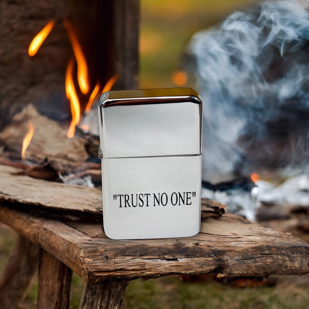 HipFlaskPlus Trust No One chrome lighter on a wooden bench beside a campfire