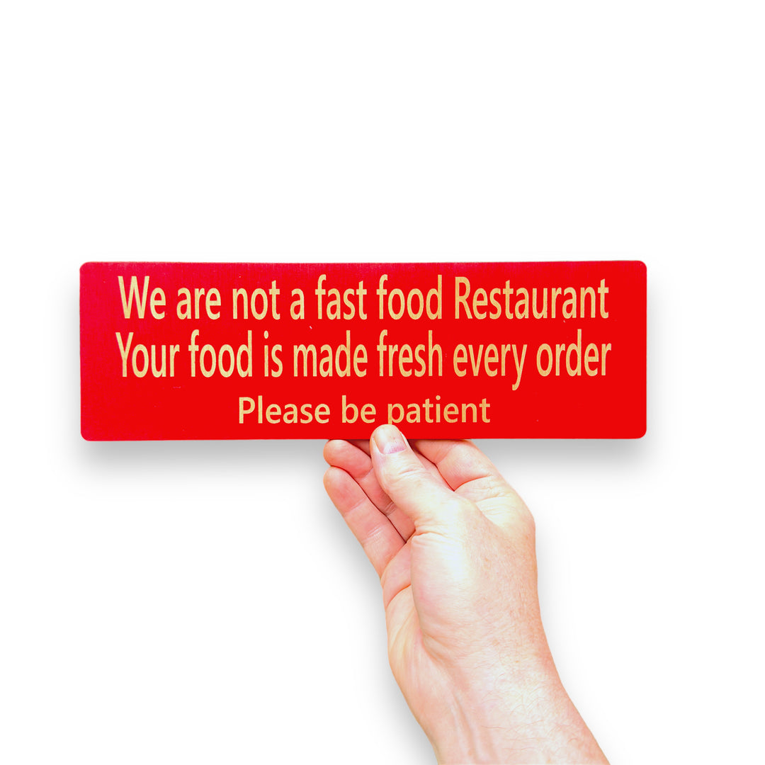Hand holding a HipFlaskPlus custom We Are Not a Fast Food Restaurant Please Be Patient sign in red