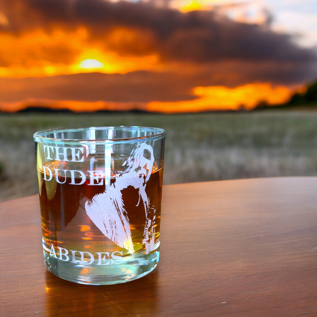 HipFlaskPlus rocks glass engraved with The Dude Abides on a table at sunset