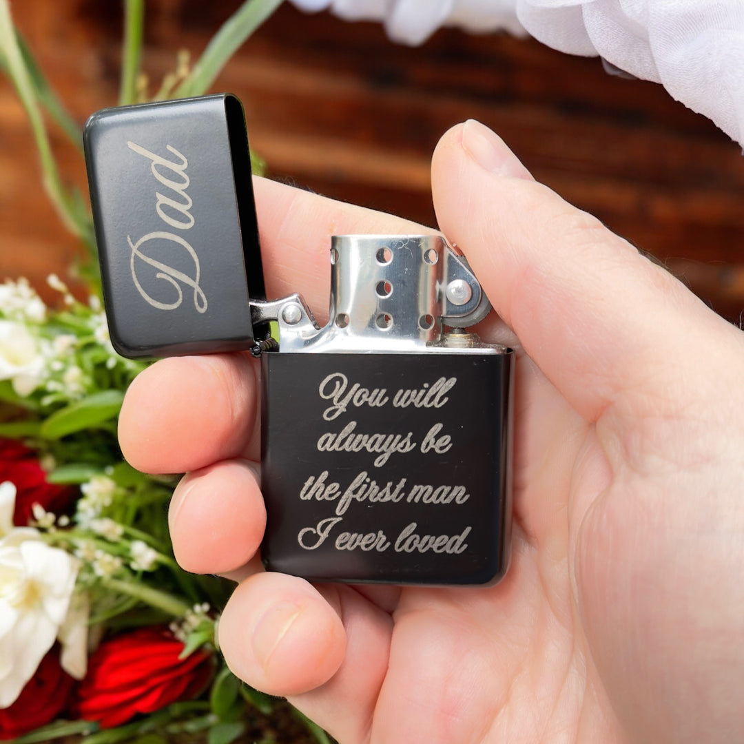 Hand holding an open HipFlaskPlus black Dad first man I ever loved lighter beside flowers