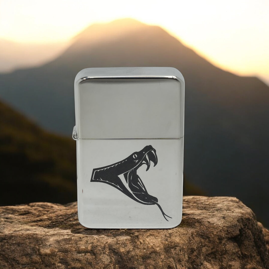 HipFlaskPlus poison viper chrome lighter on a rock with mountains at sunset
