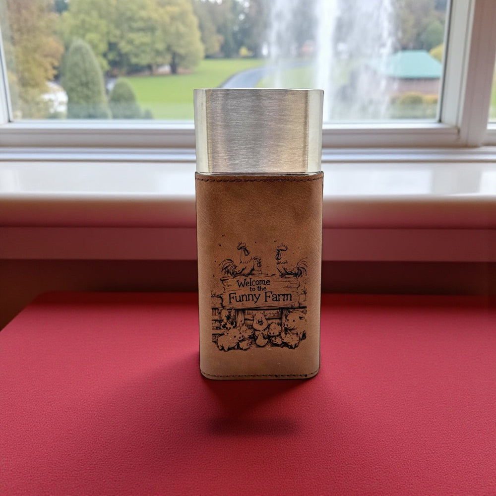 HipFlaskPlus brown leatherette cigar case with cutter engraved with Welcome to the Funny Farm on a red table by a window