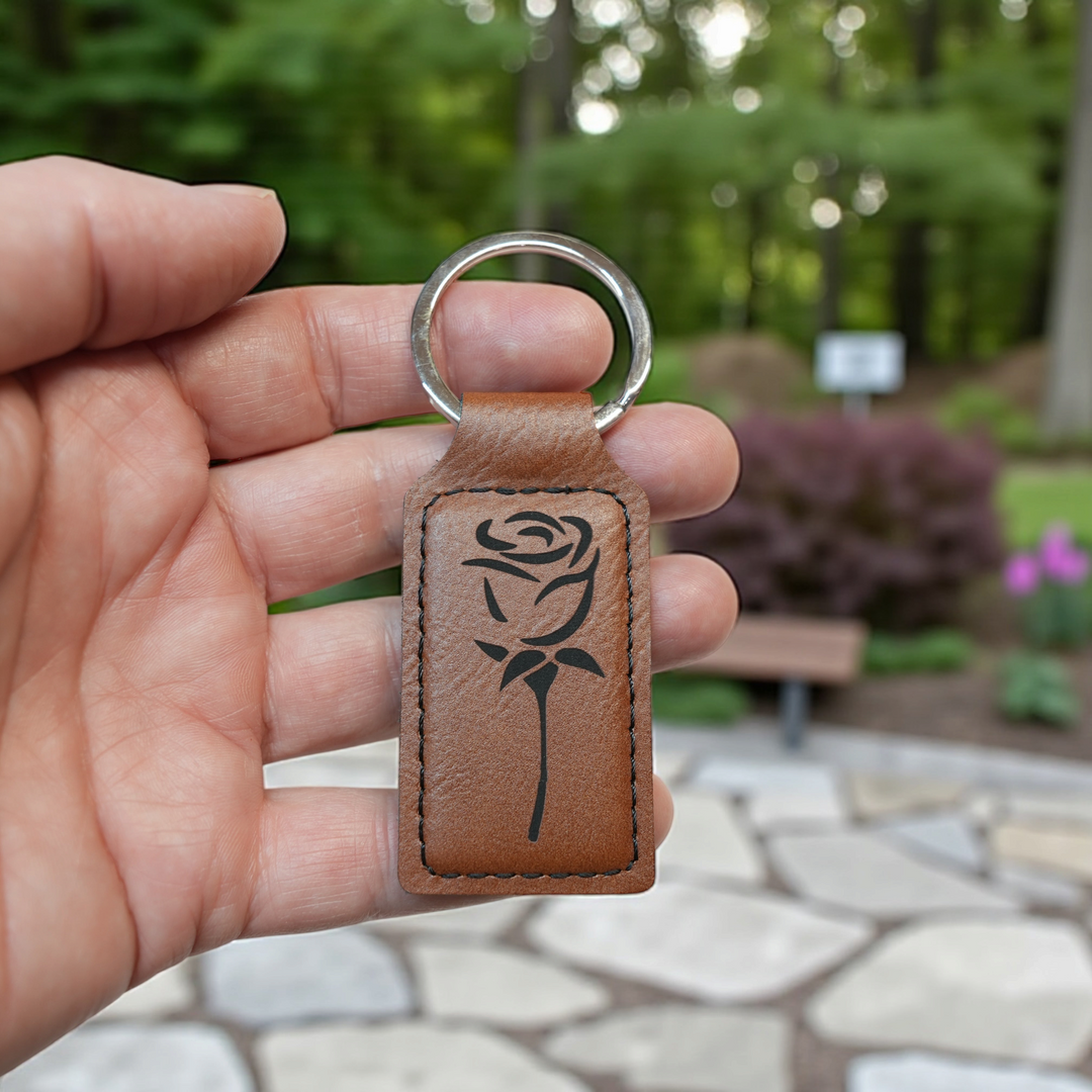 HipFlaskPlus rectangular brown leatherette keychain featuring a laser-engraved rose design held in a hand.