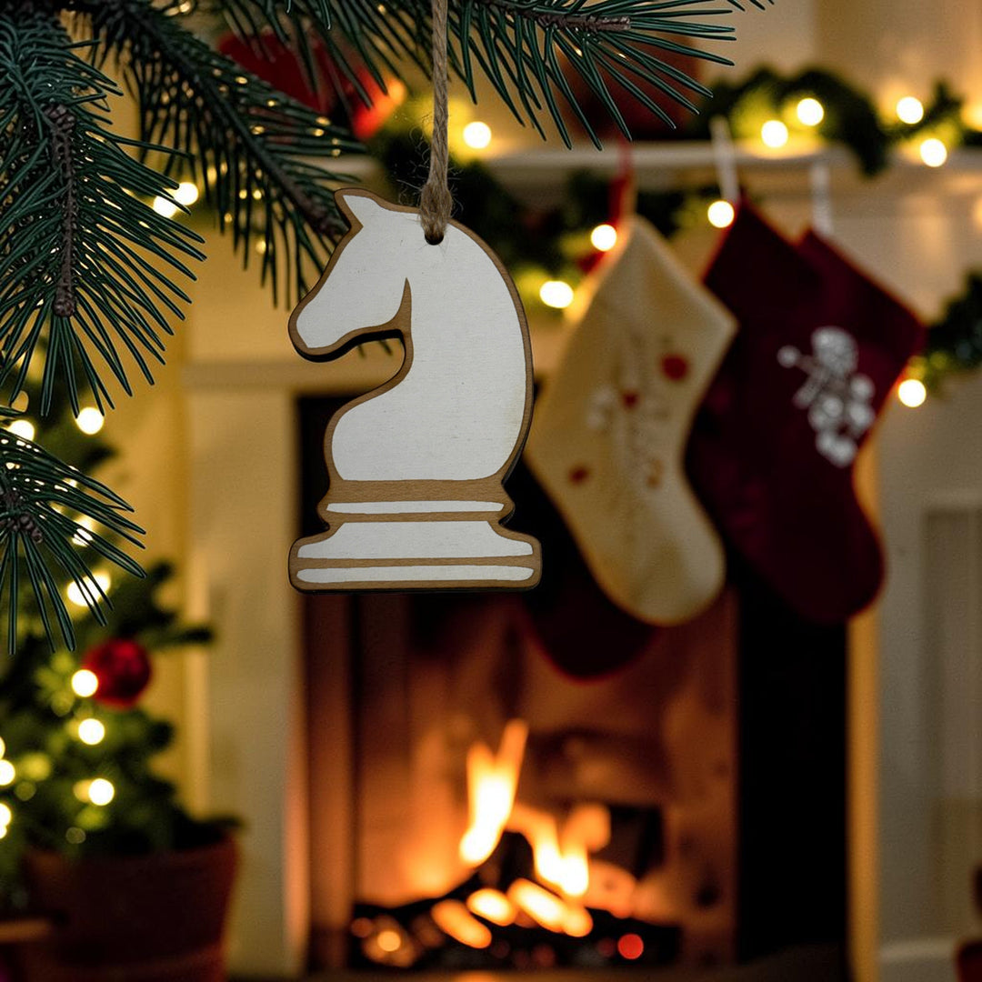 HipFlaskPlus laser-cut wooden knight chess piece ornament hanging on a Christmas tree with a fireplace background