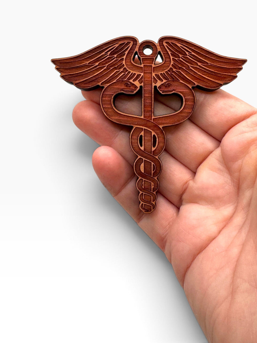 HipFlaskPlus laser-engraved wooden medical caduceus ornament held in a hand, perfect for Christmas tree decoration.