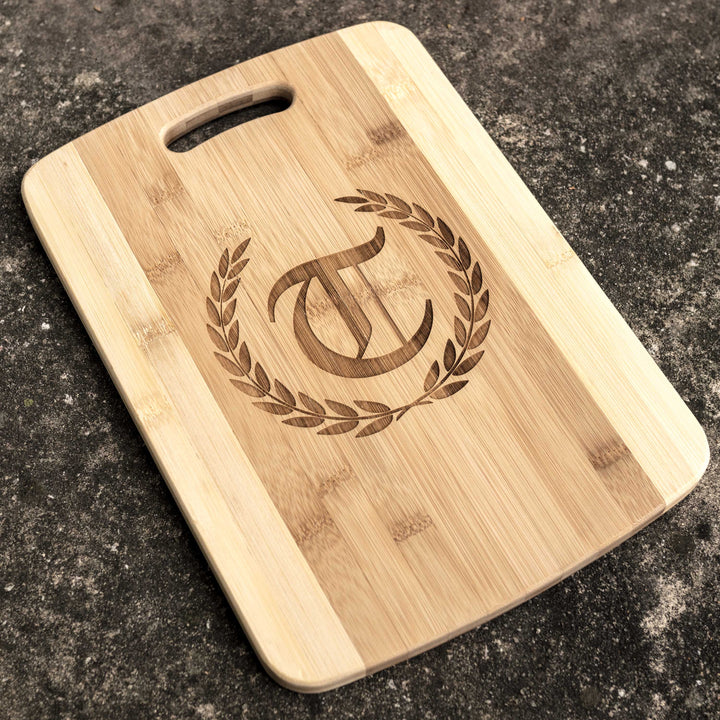HipFlaskPlus bamboo cutting board engraved with a personalized initial in a laurel wreath on dark stone