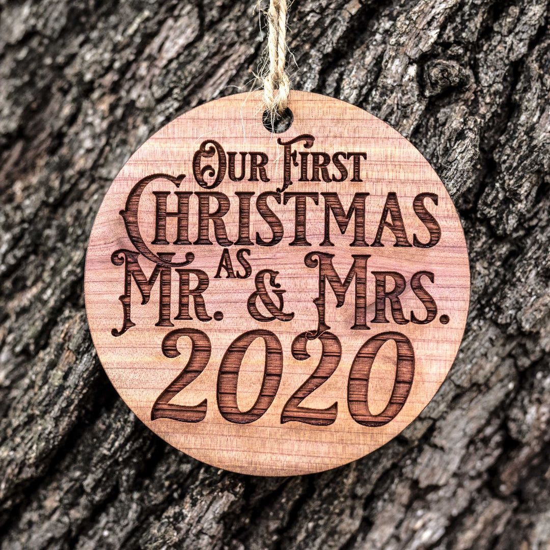 HipFlaskPlus cedar wood Our First Christmas as Mr. & Mrs. ornament hanging against tree bark